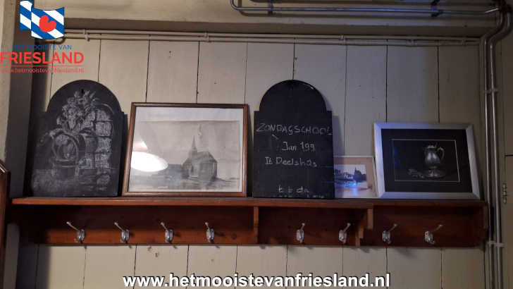 Hal van de Kapelle van Haskerdijken met kapstok, oude zwart-witfoto’s en krijtbord ‘zondagsschool’